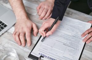 Person reviewing an auto accident insurance claims form and policy details on a clipboard