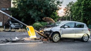 Silver car with crumpled front end after crashing into a road sign, showing the kind of damage common in car accidents
