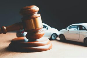 Judge's gavel beside two model cars in a rear-end collision, symbolizing how to file an auto accident claim