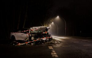 Severely damaged car wrapped in caution tape on a dark roadside, illustrating the aftermath of motor vehicle accidents