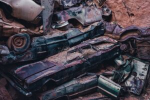 Old crushed and rusted vehicles stacked together in a rocky canyon, evoking the wreckage left behind by a multi-vehicle pileup