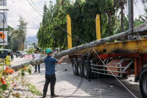 Workers assessing a downed utility pole tangled with wires after a flatbed truck collision, illustrating the scale of truck accidents