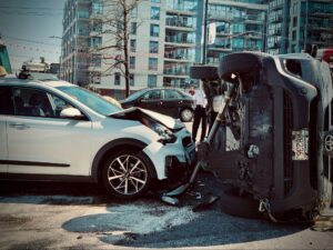 Overturned SUV resting against a damaged sedan at an accident scene, illustrating the kind of severe crash that raises the question of what is the average auto accident settlement