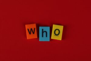 Colorful letter tiles spelling "who" on a red background representing who pays if I lose my truck accident case